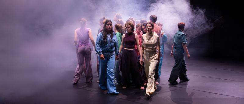 Ein großer Teil des Ensembles steht nah beieinander im Nebel. Sie bewegen sich auseinander. Über ihnen ist eine Wolke. 