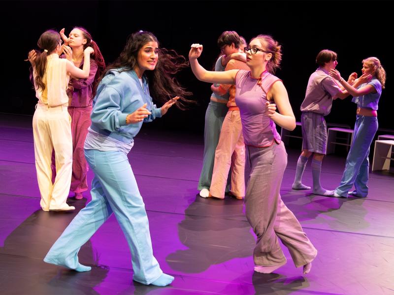 Eine Gruppe von Tänzer*innen tanzt in Zweierpaaren. Sie berühren sich dabei auf verschiedenen Arten.