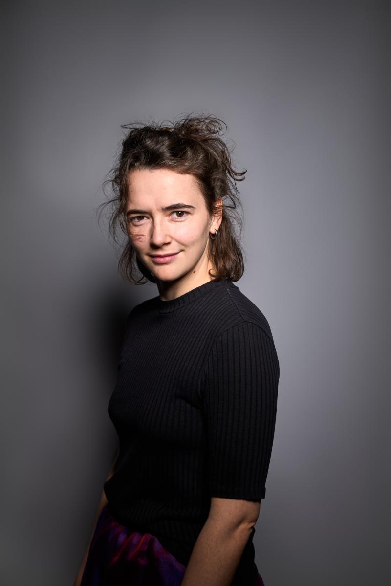 Das Bild zeigt die Schauspielerin Victoria Kraft. Sie trägt ein schwarzes Tshirt und schaut links über die Schulter in die Kamera.