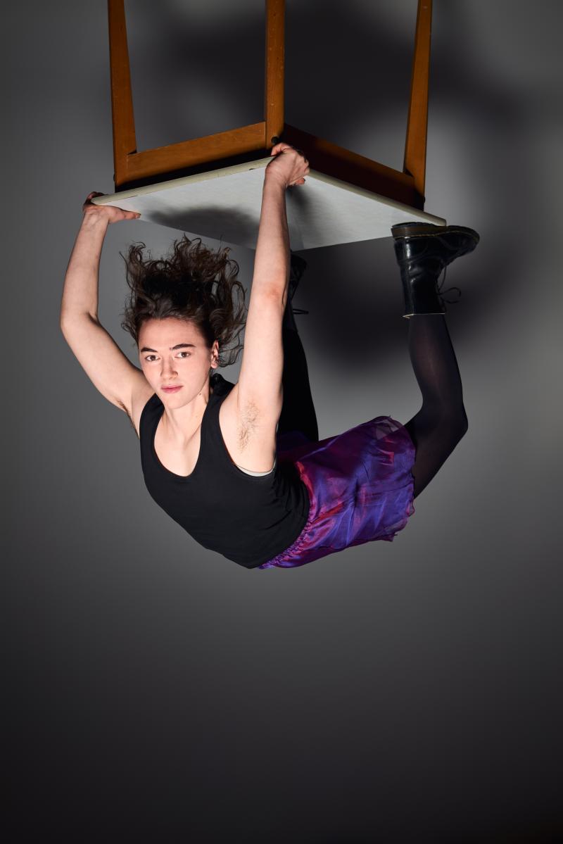 Das Bild zeigt die Schauspielerin Victoria Kraft. Sie macht eine Brücke auf einem Tisch. Das Foto ist auf dem Kopf.