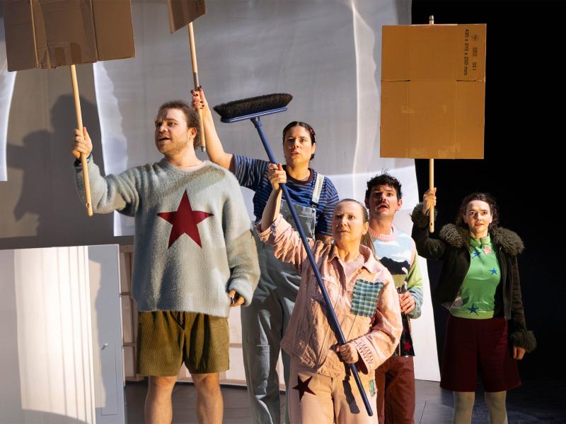 Parsa Yaghoubi Pour, Christine Ochsenhofer, Anastasia Lara Heller, Silvio Kretschmer und Victoria Kraft stehen als Gruppe zusammen. Während Christine einen Besen in die Luft hält, halten Parsa, Anastasia und Victoria Pappschilder in die Höhe. Sie blicken alle starr in eine Richtung und haben die Münder geöffnet.