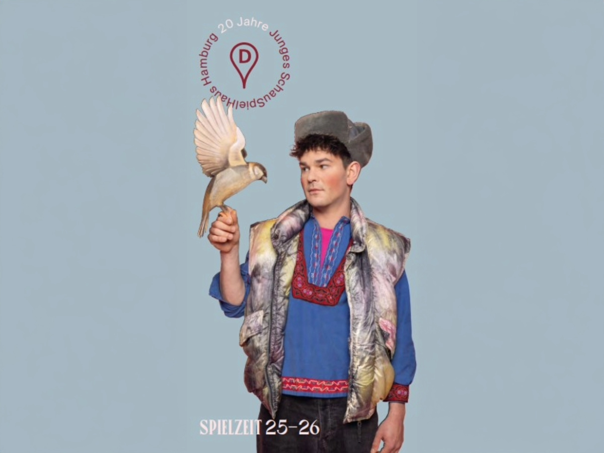 Das Cover des Spielzeitheftes der Spielzeit 2025-26: Schauspieler Silvio Kretschmer in einem blauen Hemd und einer Fellweste, mit einem Vogel aus Holz auf der Hand / fotografiert von Sinje Hasheider
