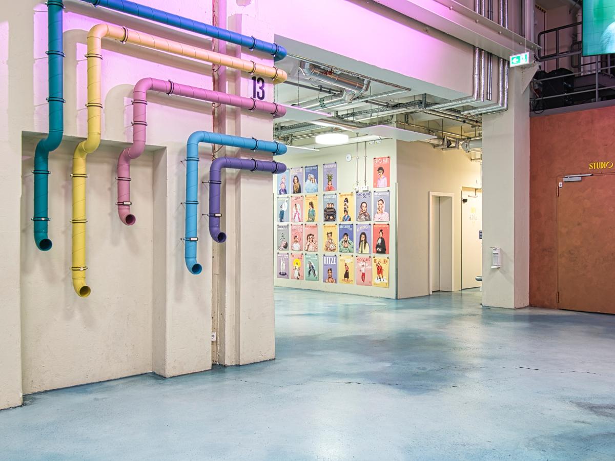 Zu sehen ist das Foyer im Jungen Schauspielhaus: Ein großer heller Raum mit bunten Wanddekorationen und Plakaten der Inszenierungen des Jungen Schauspielhauses.